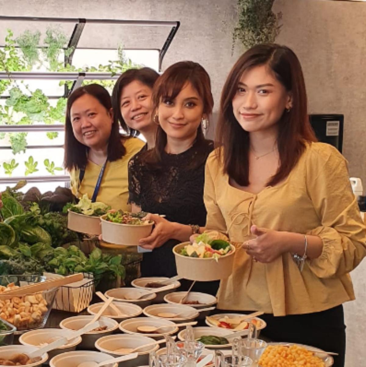 A group of women making lunch from produce they grew in a vertical garden in an office.